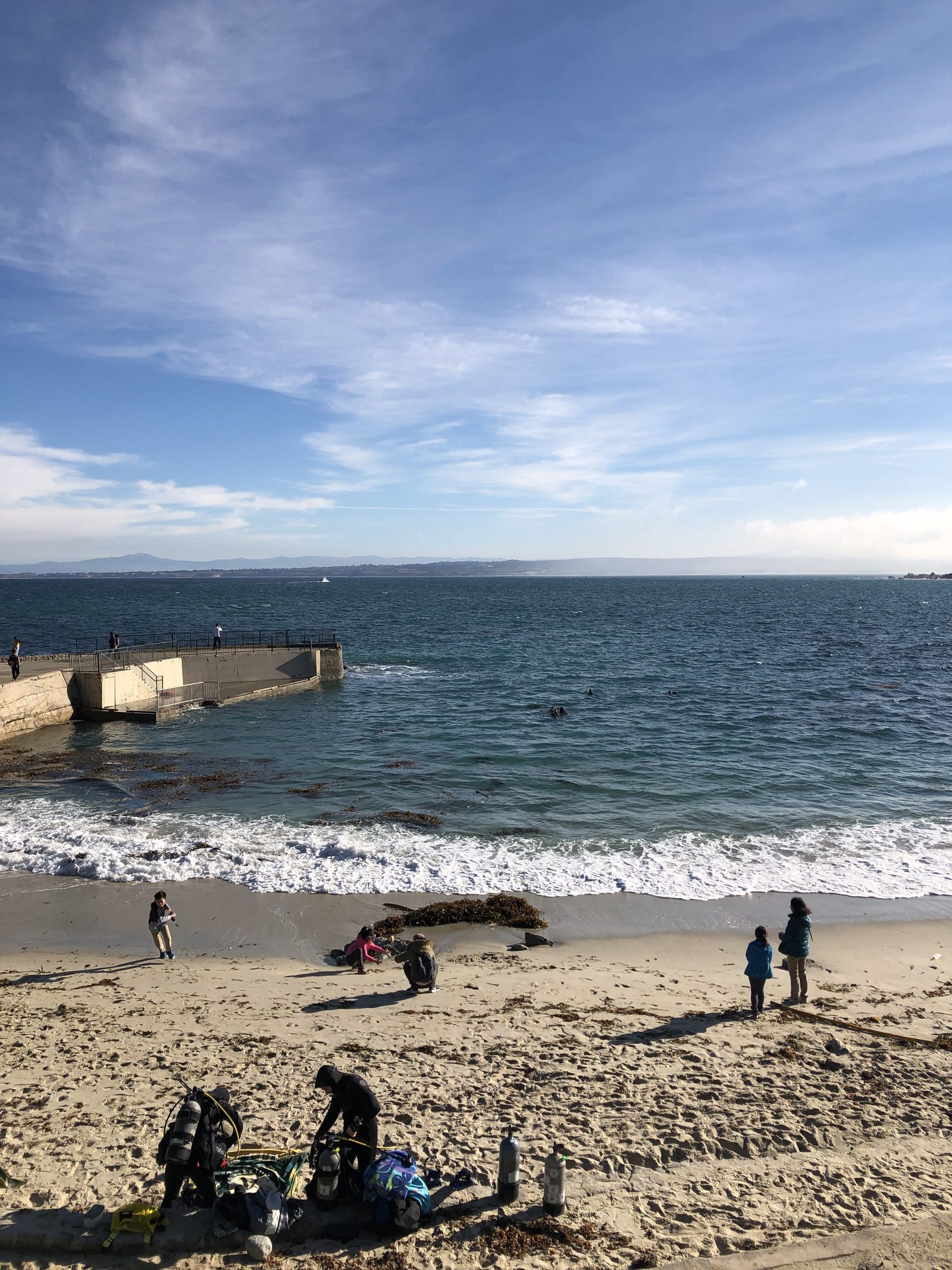 Beachgoers enjoy the sand at Lovers Point Park on Pacific Grove's rocky shoreline. The pier at the park's edge needs about $1.5 million in repairs.