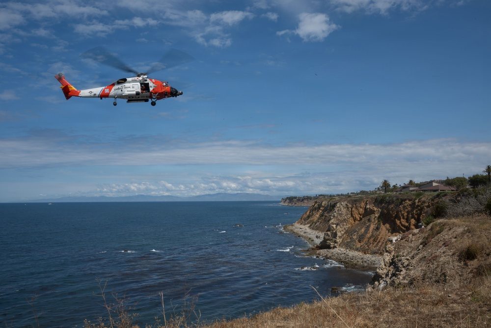A U.S. Coast Guard MH-60 Jayhawk during cliff hoist training off Point Vicente on May 5, 2026, in a training photograph. At Sand Dollar Beach, a Coast Guard helicopter hoisted Valentine from the rocky coastline and transferred him to awaiting ambulance personnel, according to the Sheriff's Office.